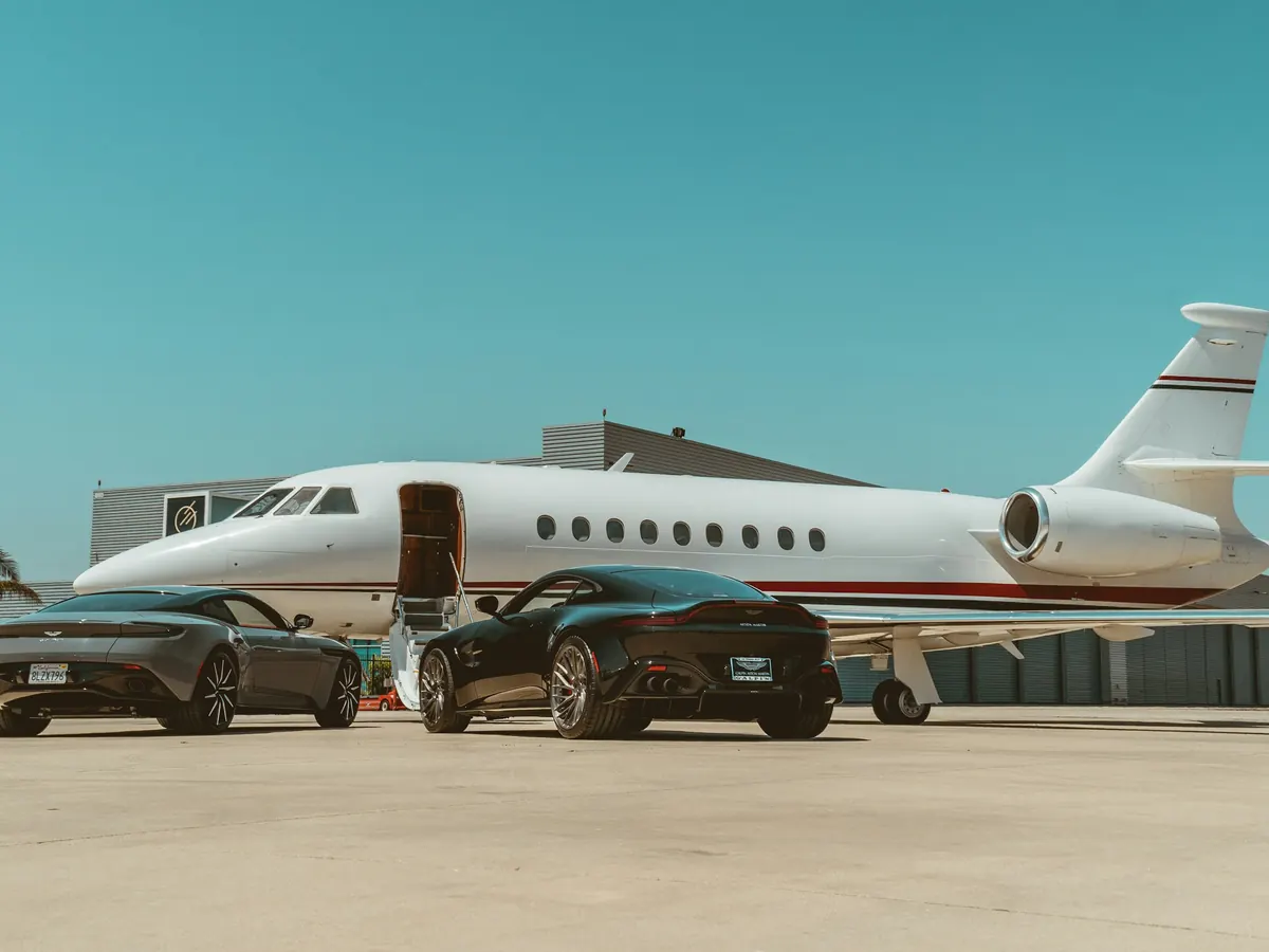 Business jet beside two cars on a sunny ramp