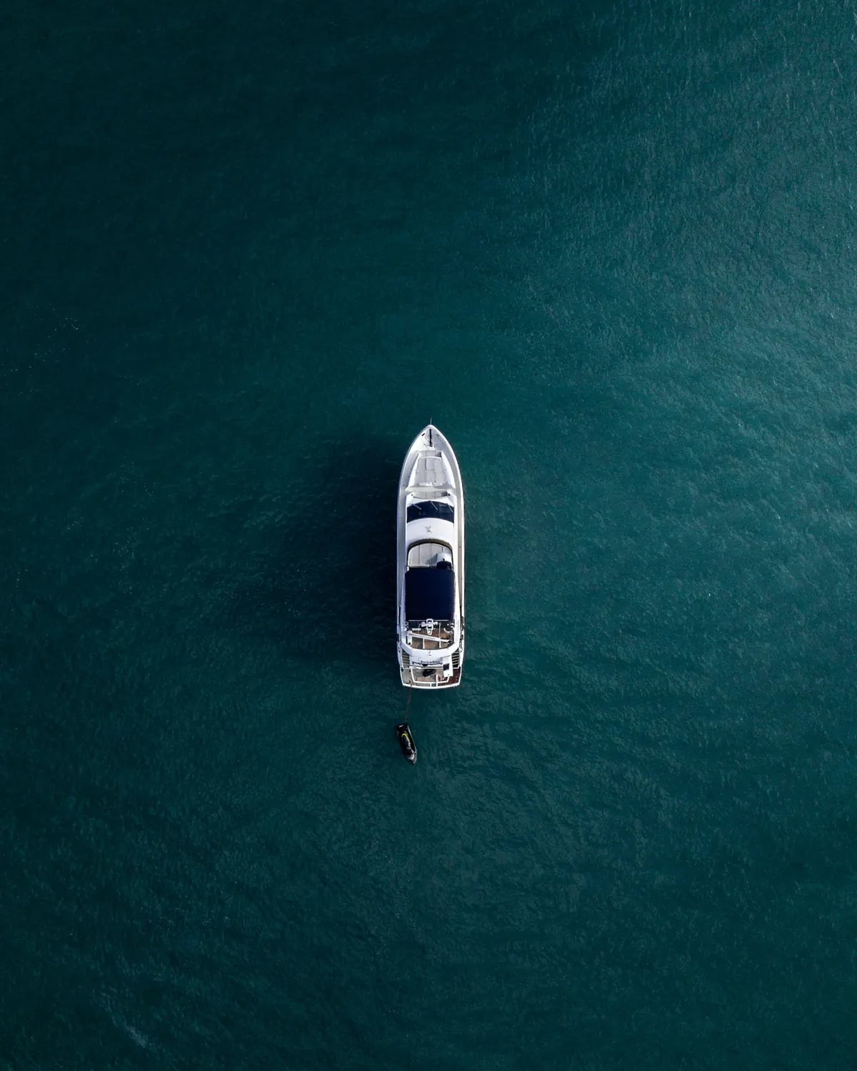 A yacht crossing deep blue water, seen from directly above